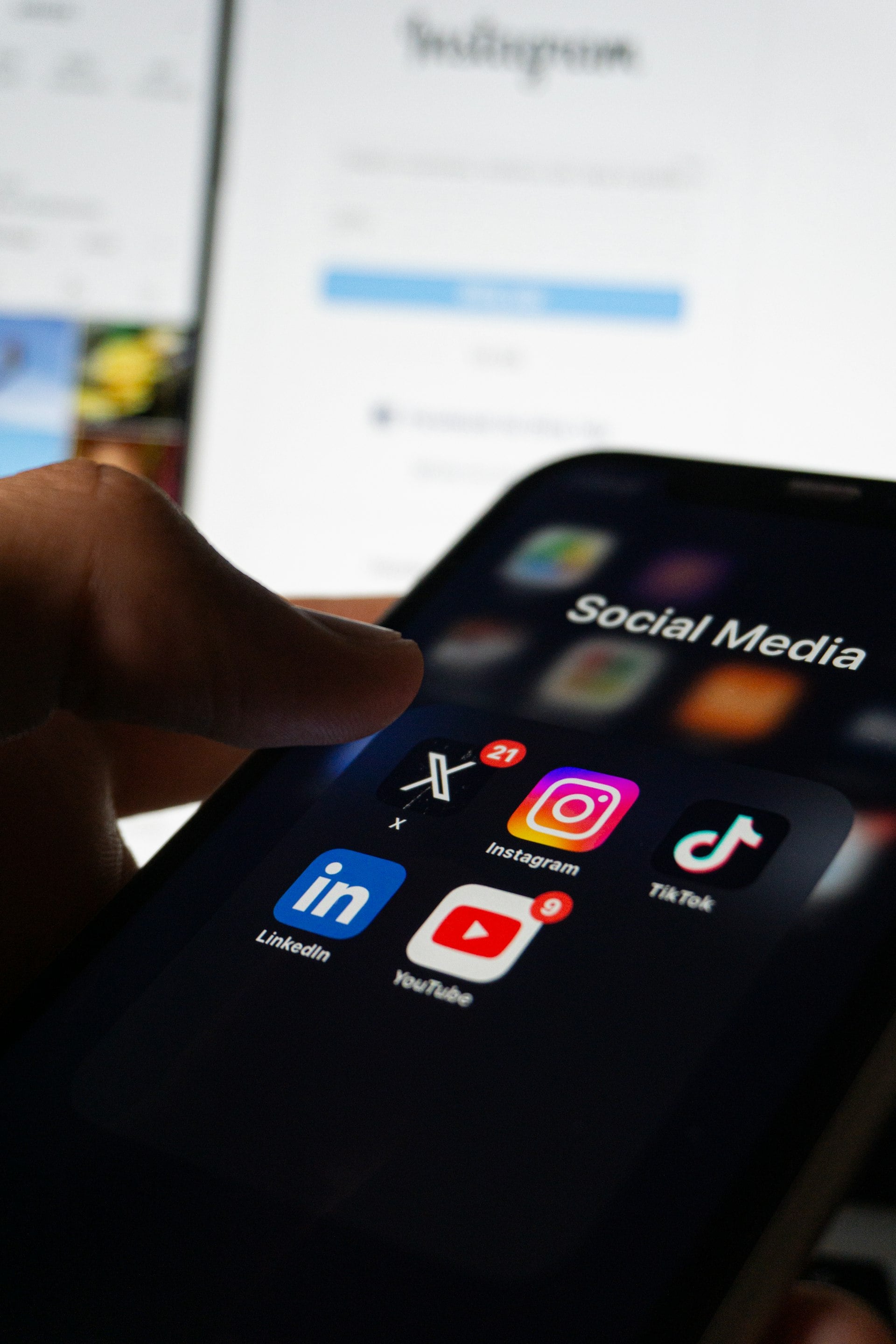 A hand holding a phone with social media apps on screen