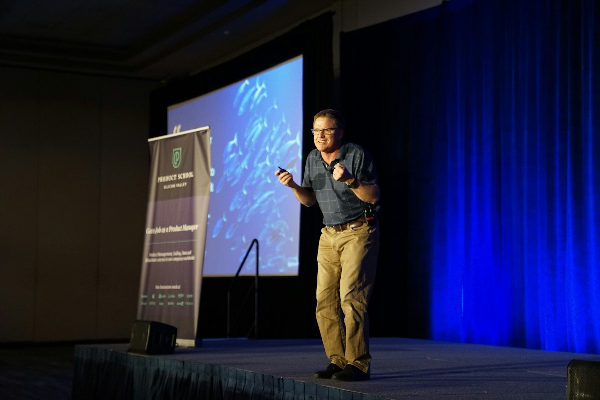 A speaker on stage in front of a projection screen